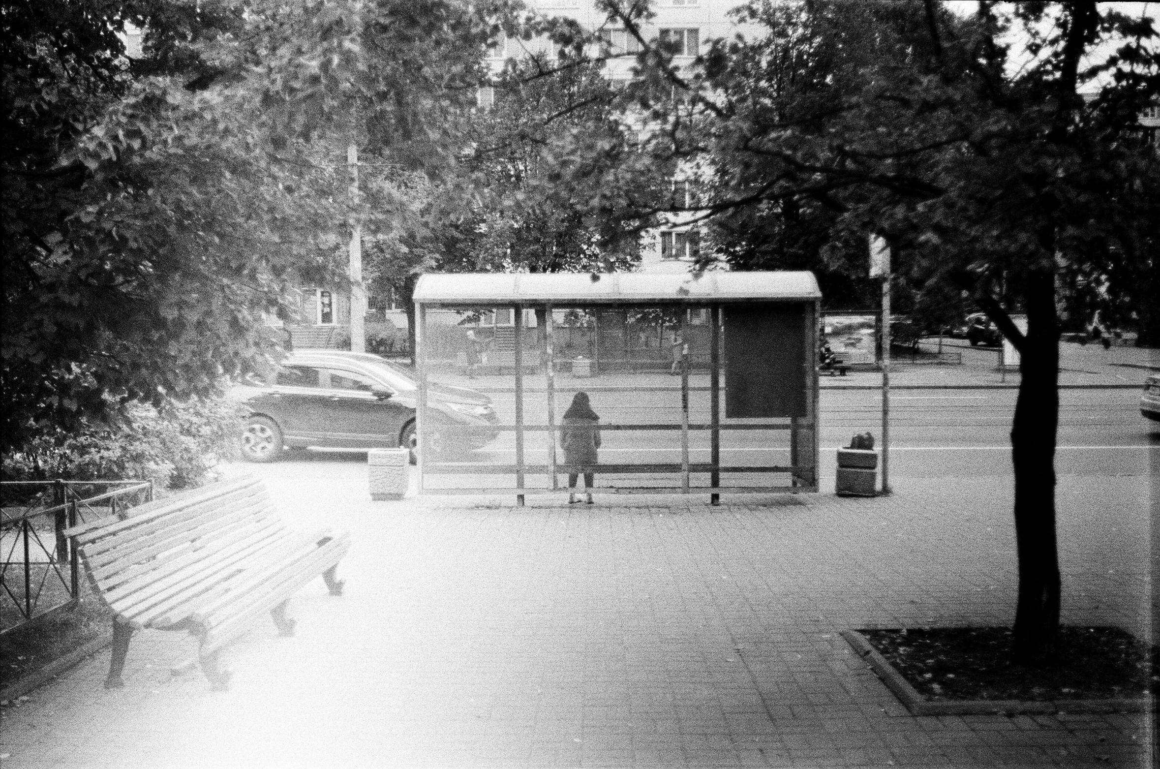 black and white pograph of a bus stop, some people