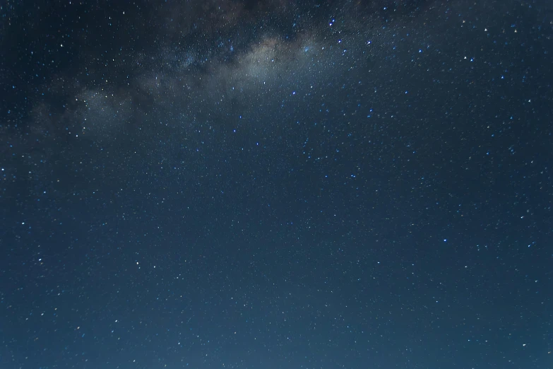 the night sky over a farm field with trees and silos