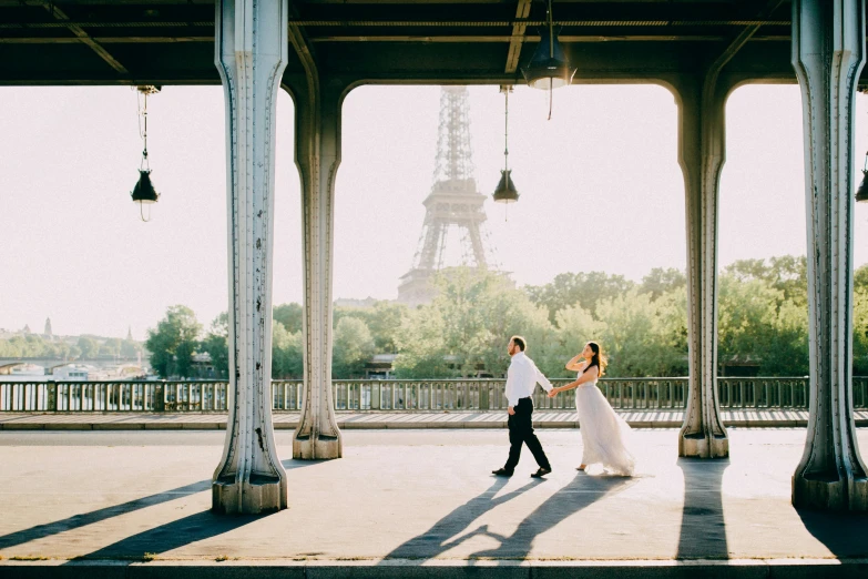 a woman is walking with a man next to her under a bridge