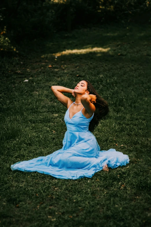 a beautiful woman in a blue dress posing on the grass