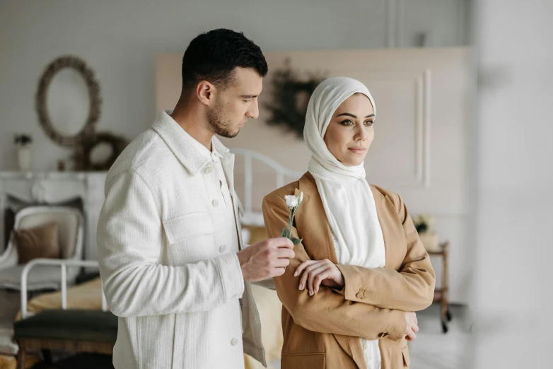 young man and woman in white and tan outfit standing beside a couch