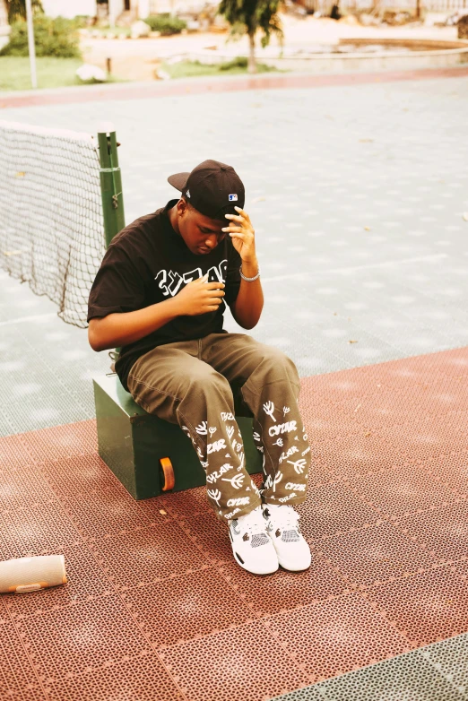 a man in black shirt and white boots sitting on green bench