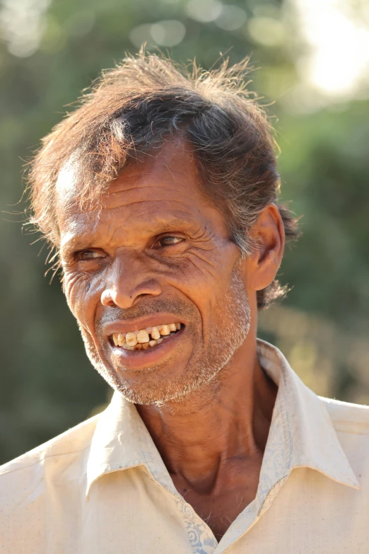 an old man smiling with his hair in a bun