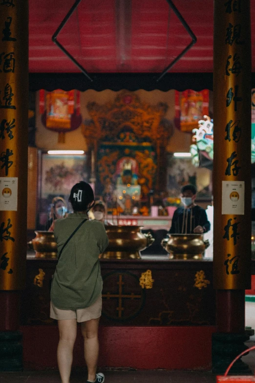 a man standing in front of a temple looking at things on display