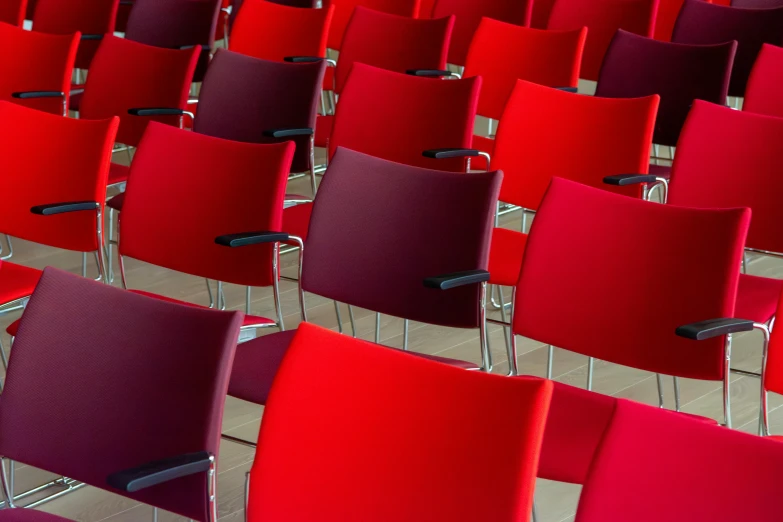 rows of chairs lined up in rows, all of red with black seats