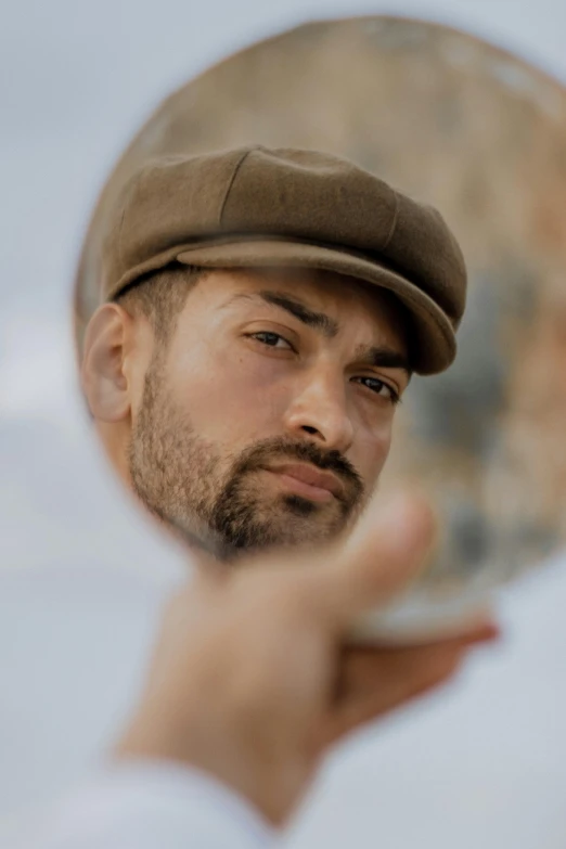 man in hat staring into mirror with soing to see