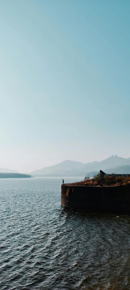 two birds sitting on an old wall that is floating in a large body of water