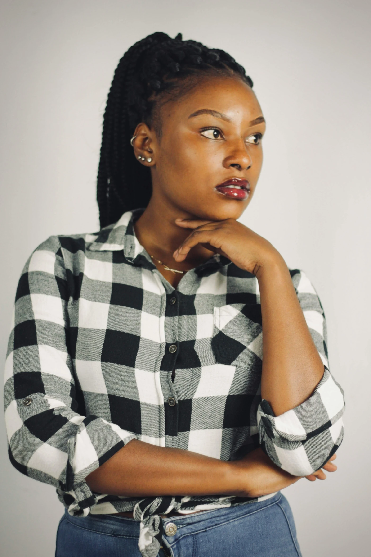 a woman poses with her chin on her chin, wearing a black and white checked shirt