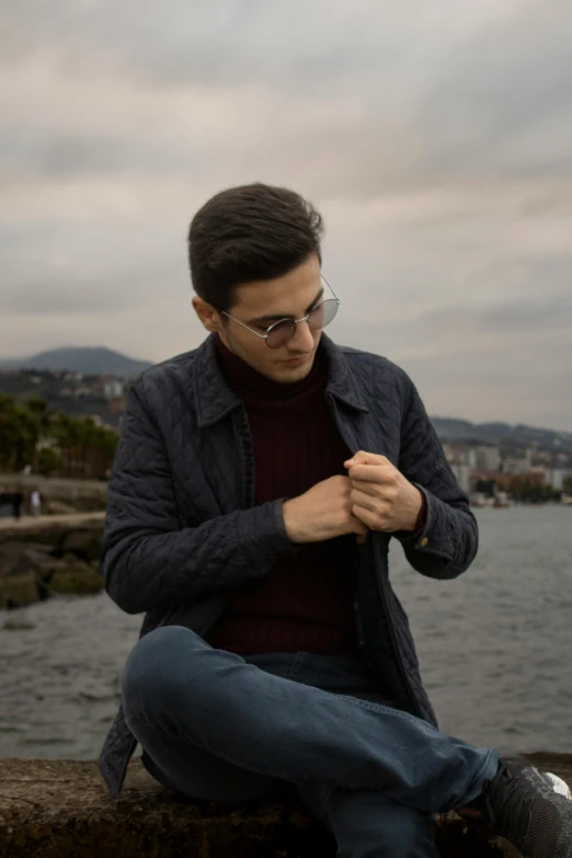 a man with glasses sitting on a rock