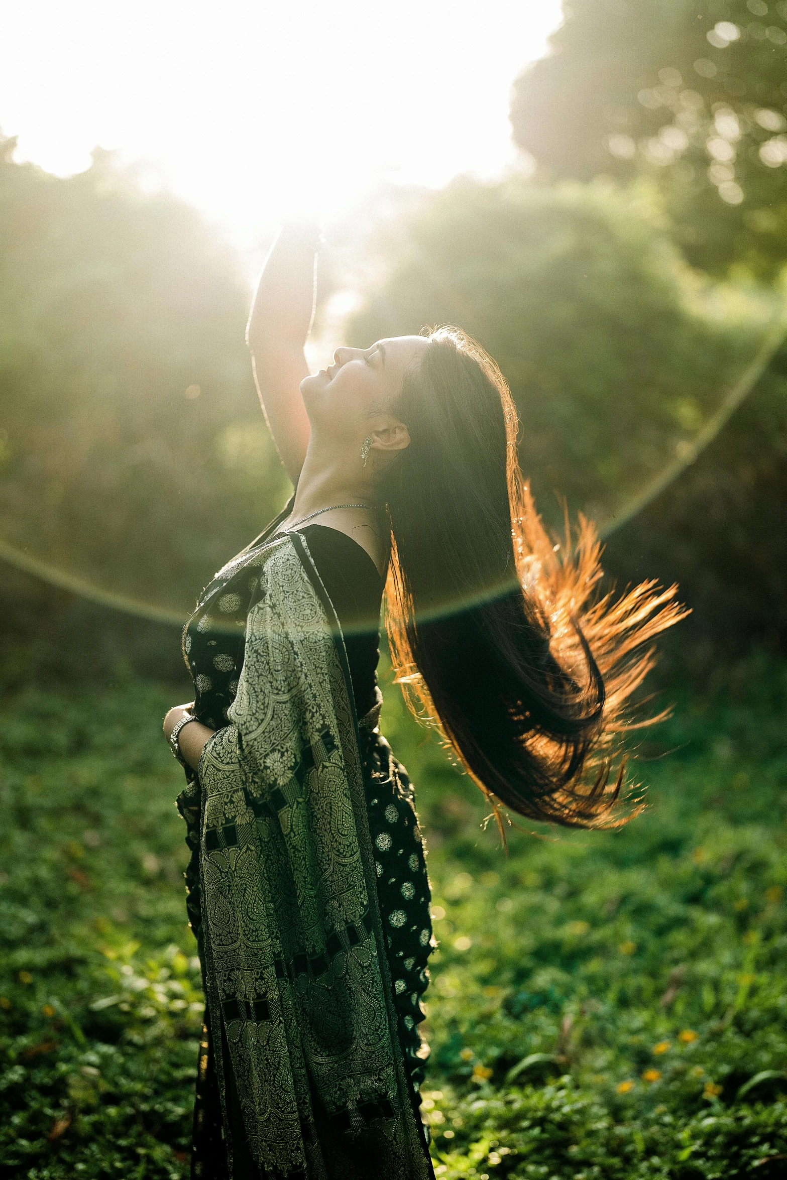 a woman is in a field and the sunlight is setting