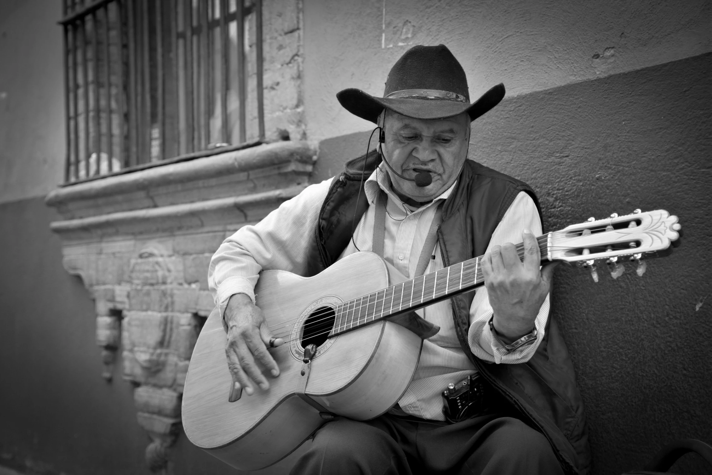 a man in a hat plays a guitar outside