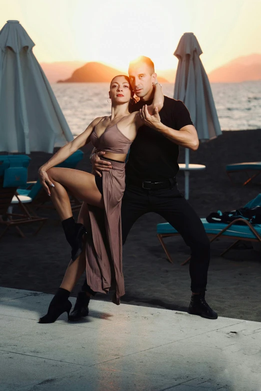 a woman standing next to a man in front of a beach