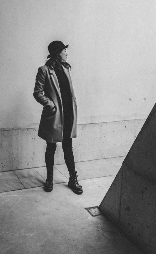 a man in black coat and hat next to cement ramp