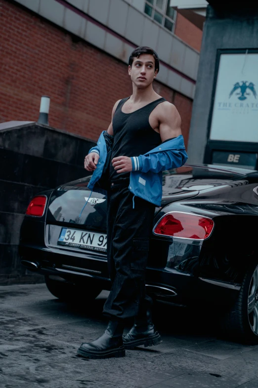 a man standing next to his parked car in the middle of the road