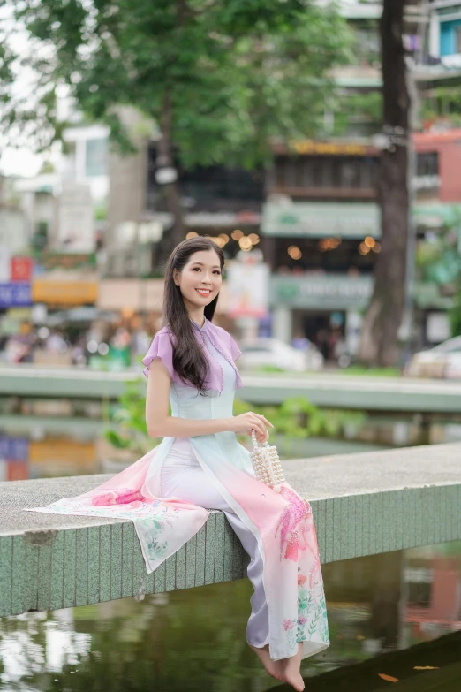 a woman in a long dress sits on a railing