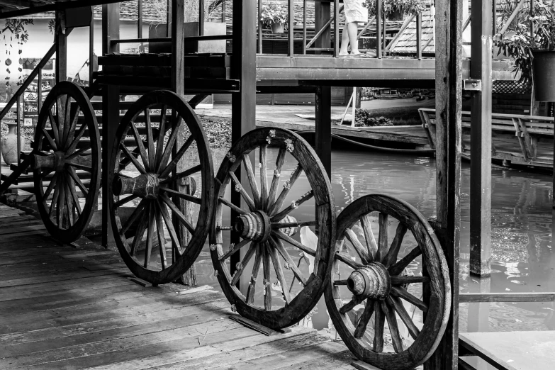 several old wheels stand on the side of a river