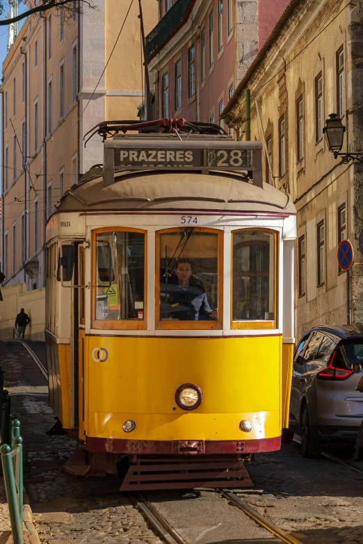 a old yellow trolley car is going down the street