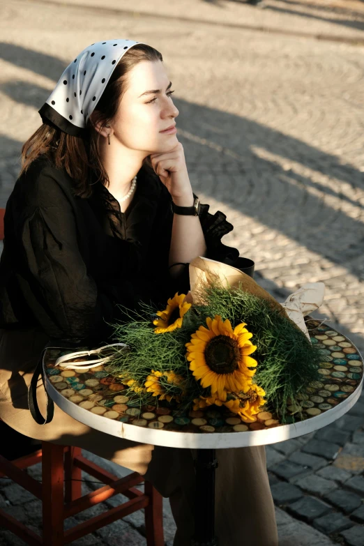 a woman sitting at a table with flowers