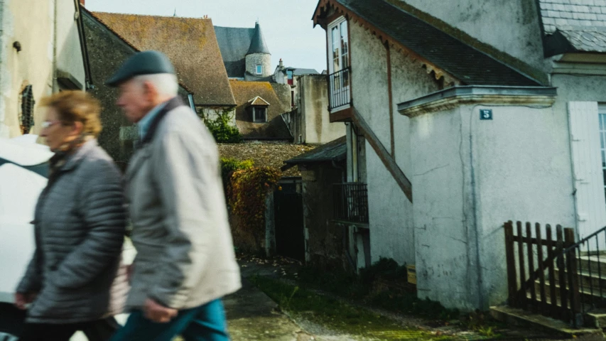 two people walking past some houses next to each other