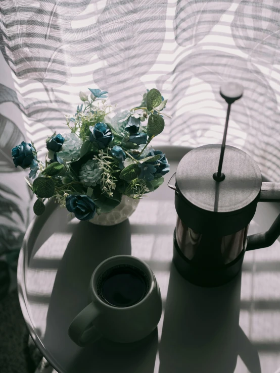 cup of coffee and teapot with flower arrangement on table
