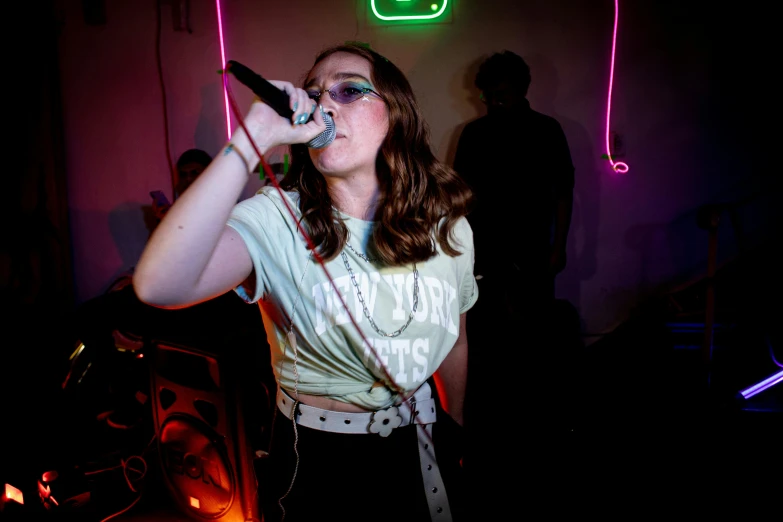 a woman singing into a microphone in a dark room