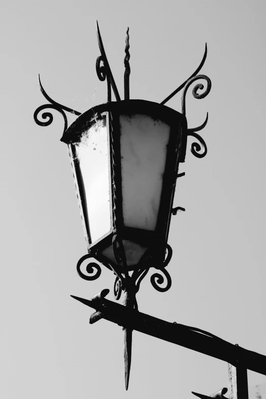 a black and white pograph of an old fashioned street lamp