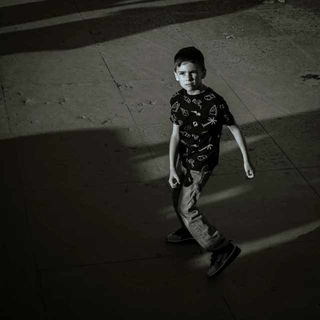 the small boy is walking on a sidewalk