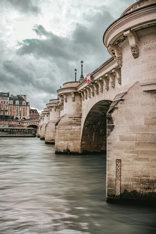 an old bridge across a river under a cloudy sky