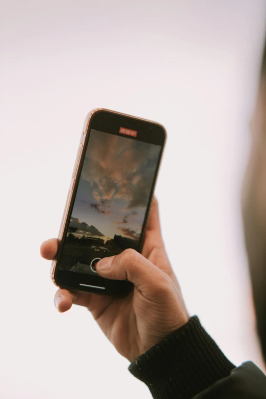 a person holding a smart phone with the sky in the background