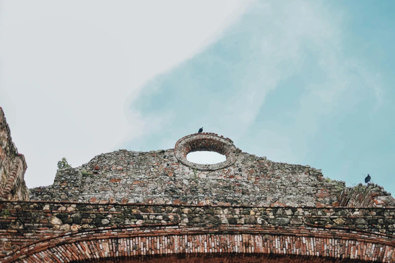 a view of an old brick arch with a pigeon standing on the arch