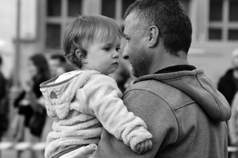 a man holds up a toddler to their face in front of a crowd