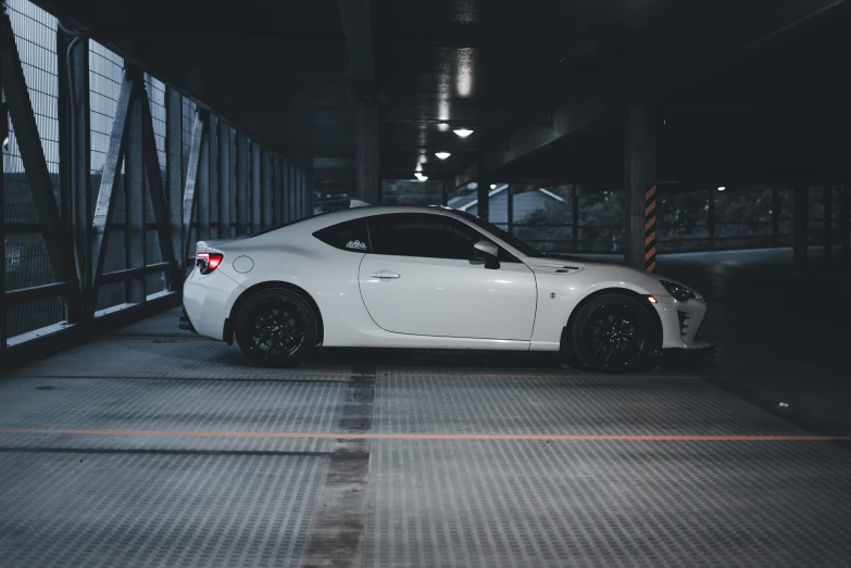 a very cute white nissan car parked in a dark parking garage