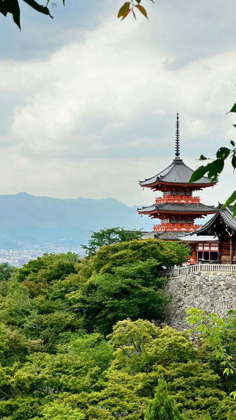 a tall building surrounded by green trees on top of a hill