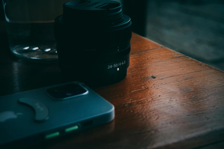 a camera lens and a cell phone sitting on top of a wooden table