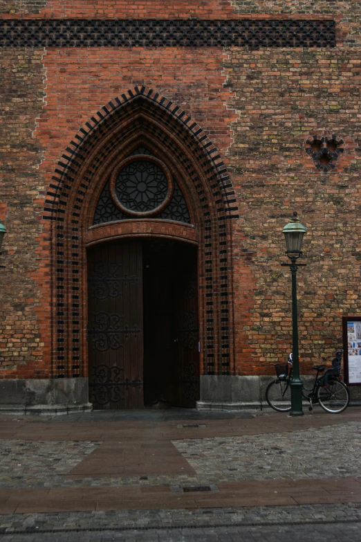 a bicycle parked against a red brick wall near a light