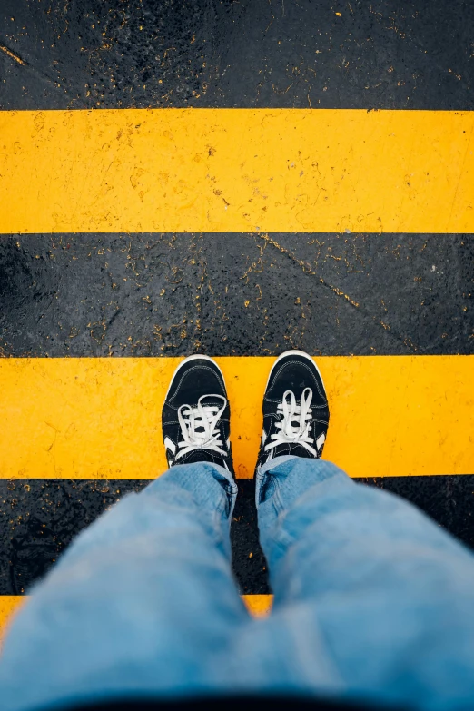 the legs and feet of a person standing in front of an yellow and black striped pattern