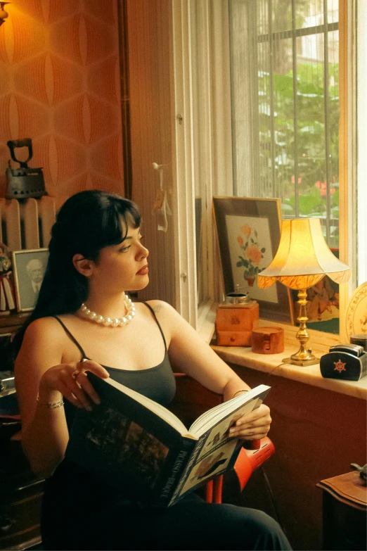 woman sitting in chair reading a book while wearing pearls