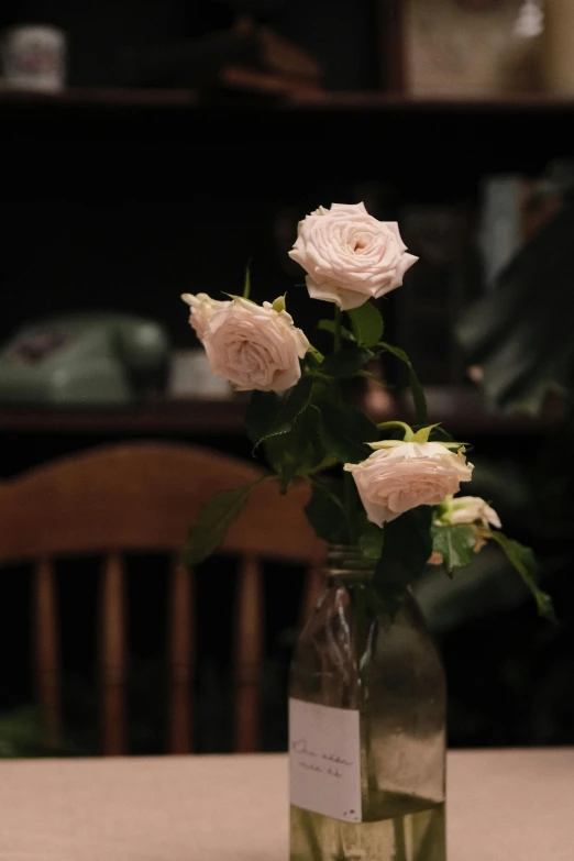 a bottle filled with pink roses sitting on top of a table