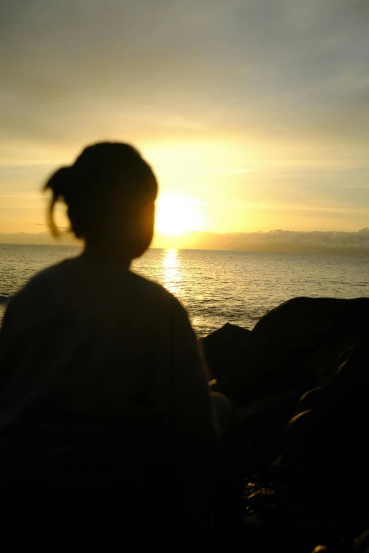 a person standing on the beach during a sunset