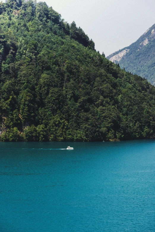 a boat on blue water surrounded by green mountains