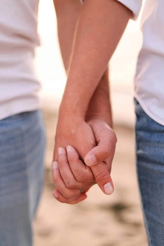 two people holding hands while on the beach