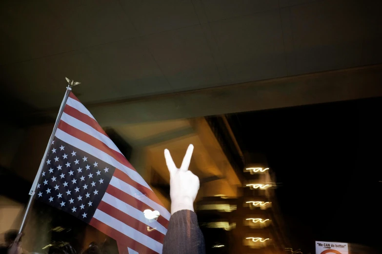 a person in dark shirt standing next to a flag