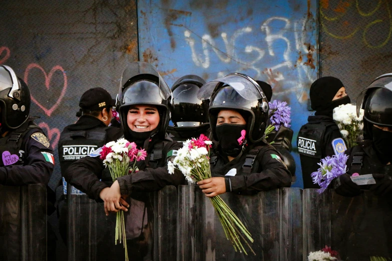 several police officers holding flowers in front of graffiti