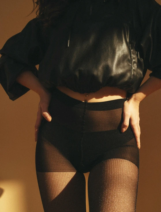 a woman in sheer stockings and black jacket posing