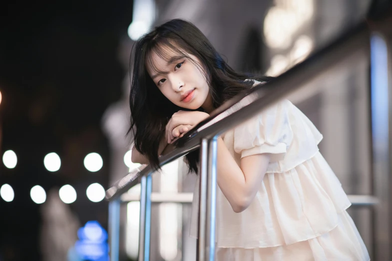 a woman wearing white is leaning against a railing