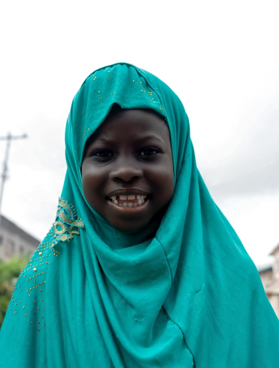 a woman in a blue hijab is smiling