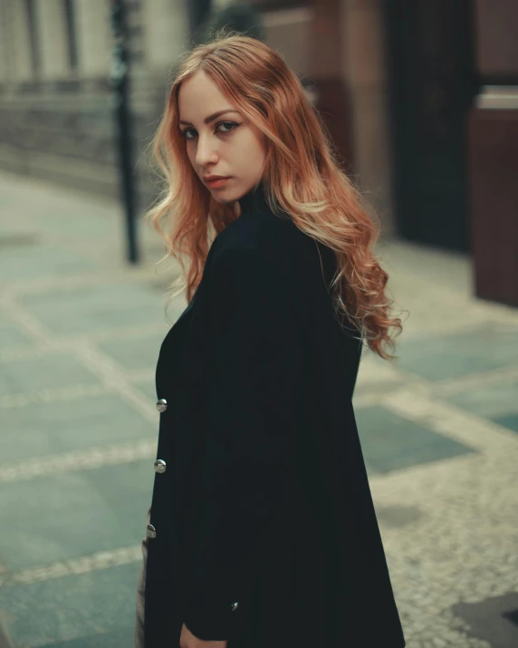 a woman with long blonde hair standing near a street