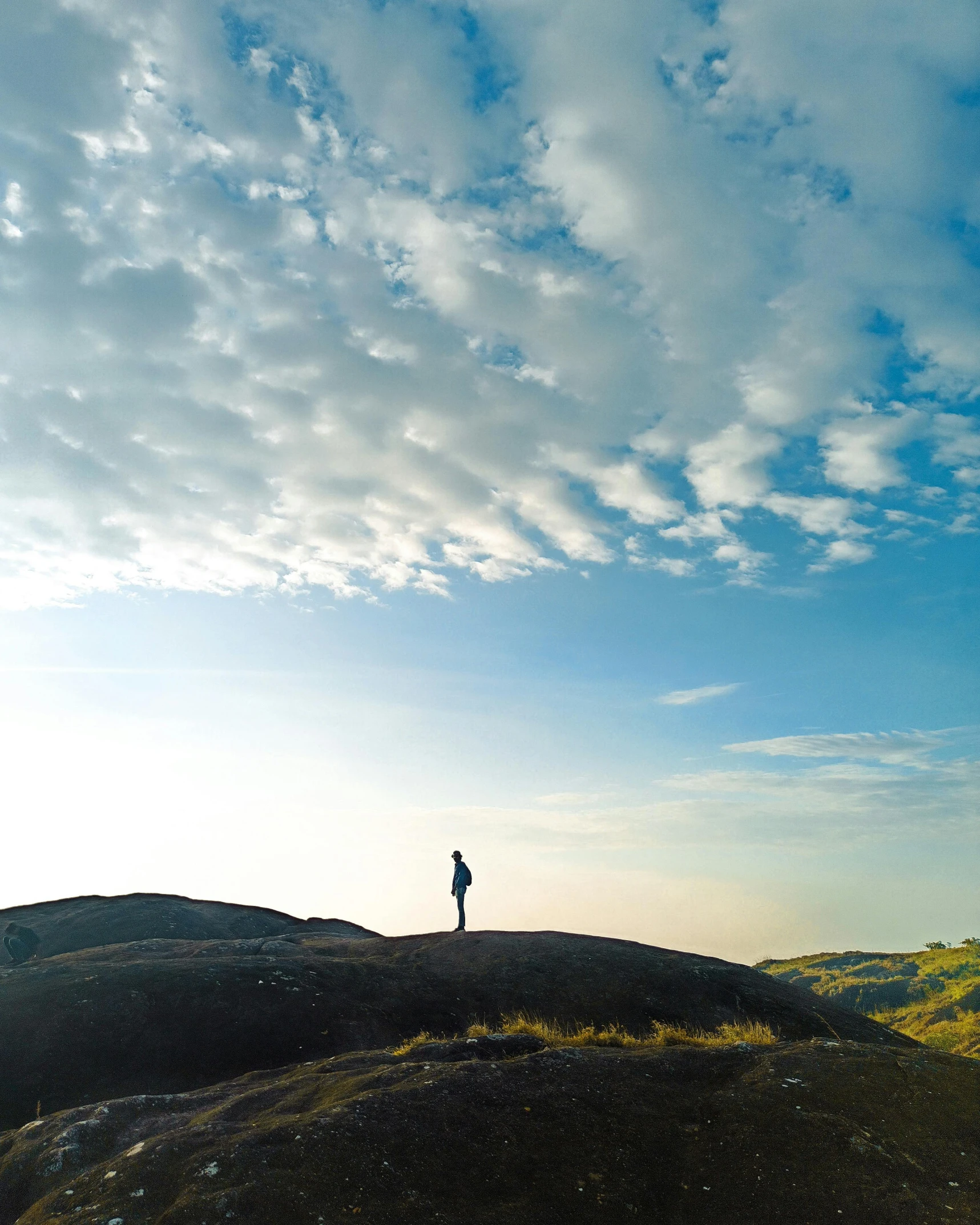 a person standing on top of a hill with a blue sky