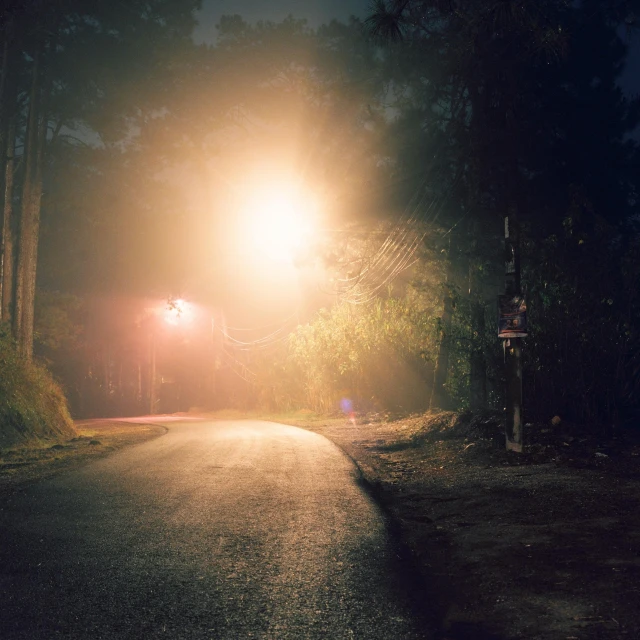 the street is dimly lit from the bright street light