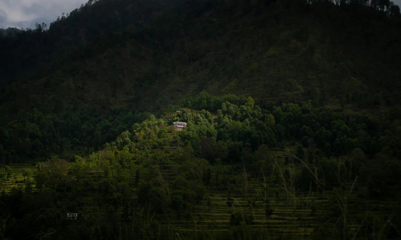 a small building nestled in the middle of a green valley